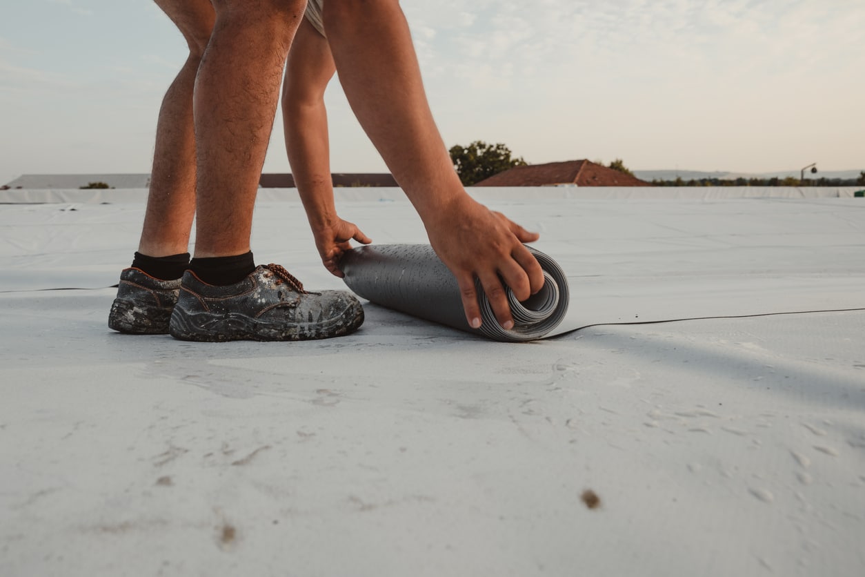 Worker applies pvc membrane roller on roof very carefully